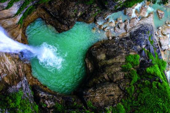 Aerial photo of a waterfall and a green pool