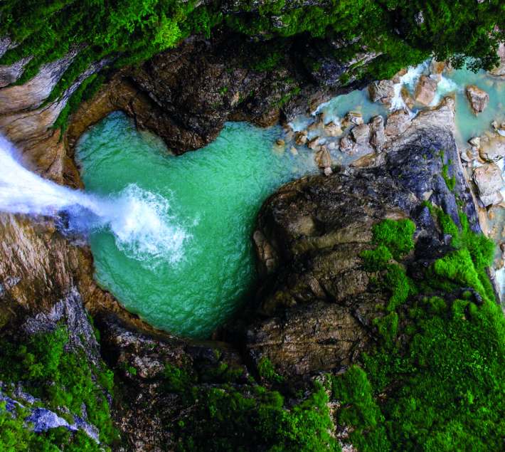 Aerial photo of a waterfall and a green pool